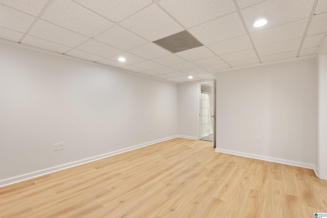 spare room with light wood finished floors, a drop ceiling, recessed lighting, and baseboards