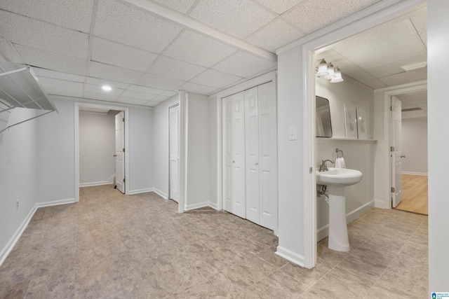 interior space featuring a sink, a drop ceiling, and baseboards