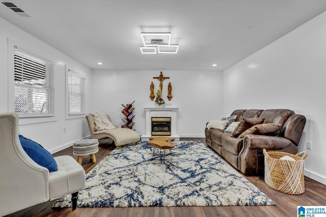 living room featuring visible vents, wood finished floors, a glass covered fireplace, recessed lighting, and baseboards