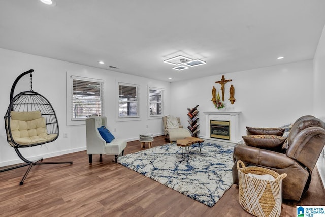 living room with visible vents, baseboards, recessed lighting, wood finished floors, and a glass covered fireplace