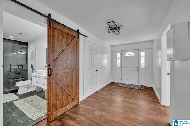 foyer featuring a barn door, wood finished floors, and baseboards