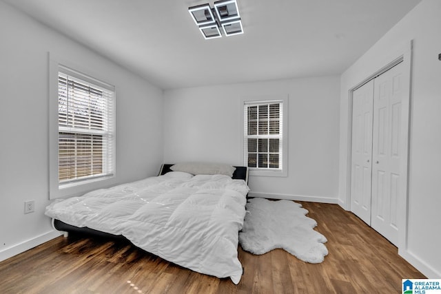 bedroom with wood finished floors, baseboards, and a closet