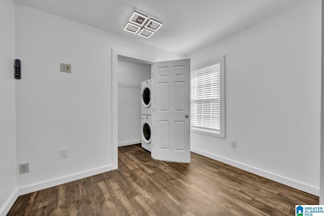 laundry area with stacked washer / dryer, wood finished floors, and baseboards