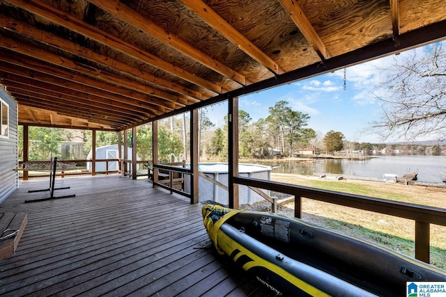 deck featuring an outbuilding, a storage unit, a water view, and a boat dock