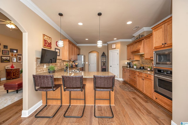 kitchen with visible vents, appliances with stainless steel finishes, a peninsula, arched walkways, and a sink