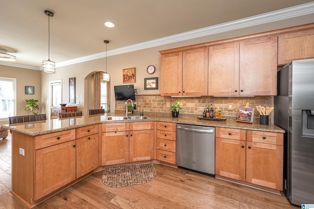 kitchen with a peninsula, arched walkways, a sink, stainless steel appliances, and light wood-style floors