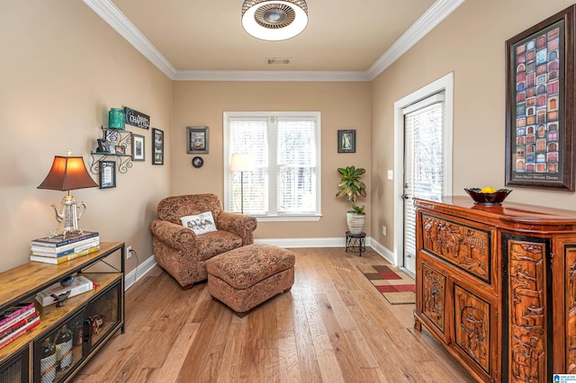 sitting room with light wood finished floors, visible vents, baseboards, and ornamental molding