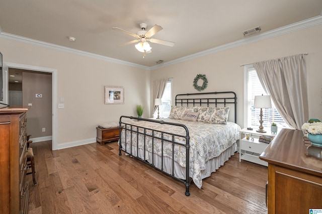 bedroom with visible vents, multiple windows, wood finished floors, and ornamental molding