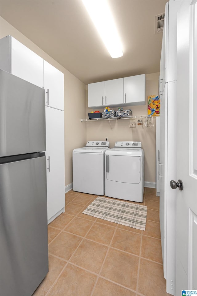 washroom with visible vents, cabinet space, light tile patterned floors, baseboards, and washing machine and clothes dryer