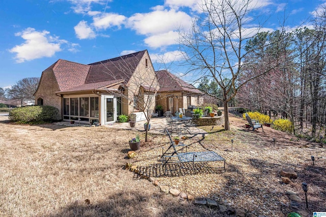 rear view of property featuring a shingled roof, a patio, and a sunroom