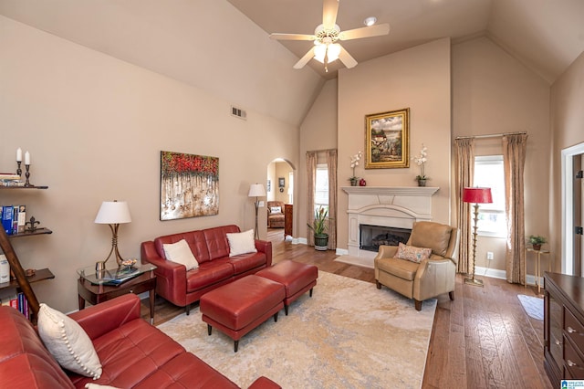 living room with visible vents, a ceiling fan, hardwood / wood-style floors, arched walkways, and baseboards