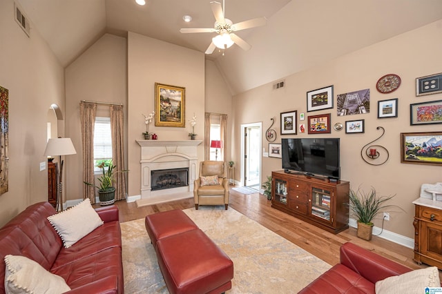 living room with visible vents, a fireplace with raised hearth, a ceiling fan, and wood finished floors