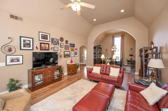 living area with visible vents, wood finished floors, arched walkways, ceiling fan, and vaulted ceiling