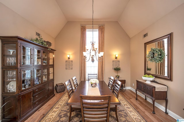 dining space with visible vents, lofted ceiling, light wood-style floors, an inviting chandelier, and baseboards