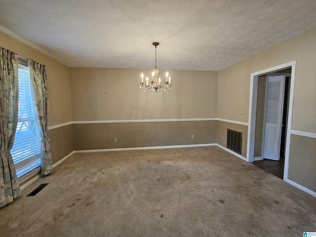 carpeted empty room with an inviting chandelier, visible vents, and a textured ceiling