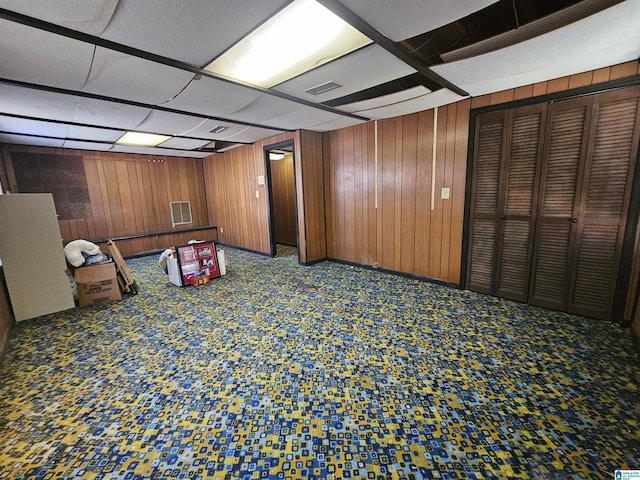 rec room featuring visible vents, a paneled ceiling, and wood walls