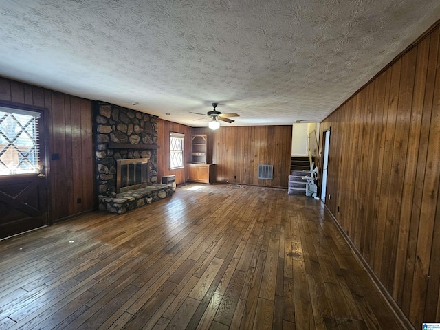 unfurnished living room featuring stairway, a textured ceiling, dark wood-style floors, and a fireplace