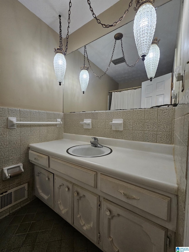 full bath with tile patterned floors, visible vents, tile walls, wainscoting, and vanity