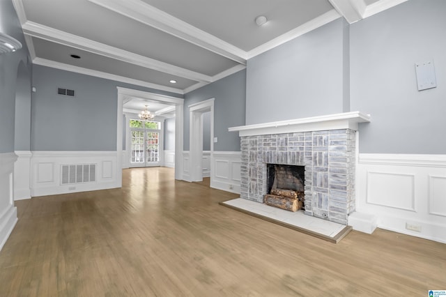 unfurnished living room featuring beamed ceiling, a decorative wall, a fireplace with raised hearth, and visible vents