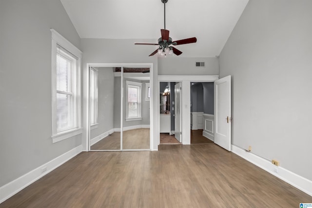 unfurnished bedroom featuring visible vents, multiple windows, lofted ceiling, and wood finished floors