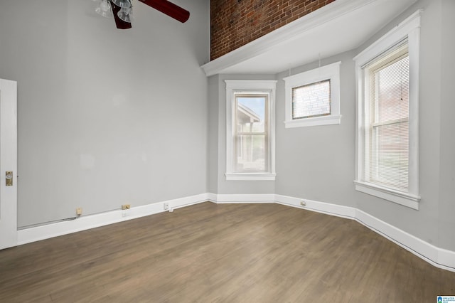 empty room featuring a ceiling fan, baseboards, and wood finished floors