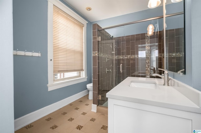 bathroom with vanity, toilet, baseboards, and a stall shower