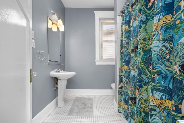 bathroom with a shower with curtain, baseboards, a sink, tile patterned flooring, and toilet