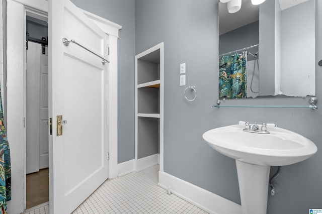 bathroom featuring curtained shower, baseboards, and a sink