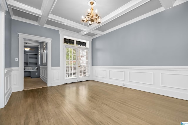 unfurnished dining area with wood finished floors, a wainscoted wall, coffered ceiling, ornamental molding, and beamed ceiling