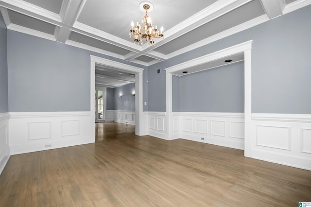 unfurnished room with beam ceiling, coffered ceiling, an inviting chandelier, and wood finished floors