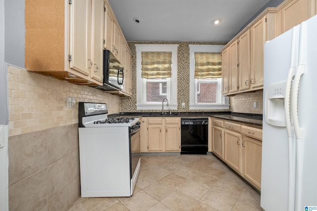 kitchen featuring light tile patterned floors, light brown cabinetry, a sink, black appliances, and dark countertops