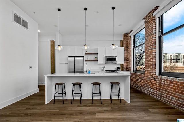 kitchen with visible vents, dark wood-style floors, white cabinetry, appliances with stainless steel finishes, and brick wall