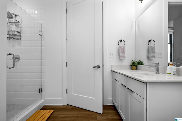 full bath with a shower stall, vanity, baseboards, and wood finished floors