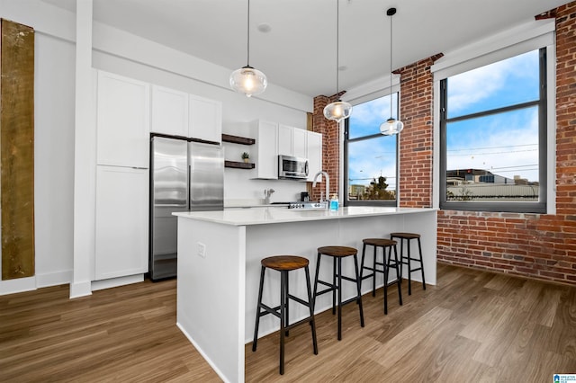 kitchen with dark wood-style floors, appliances with stainless steel finishes, brick wall, and a breakfast bar