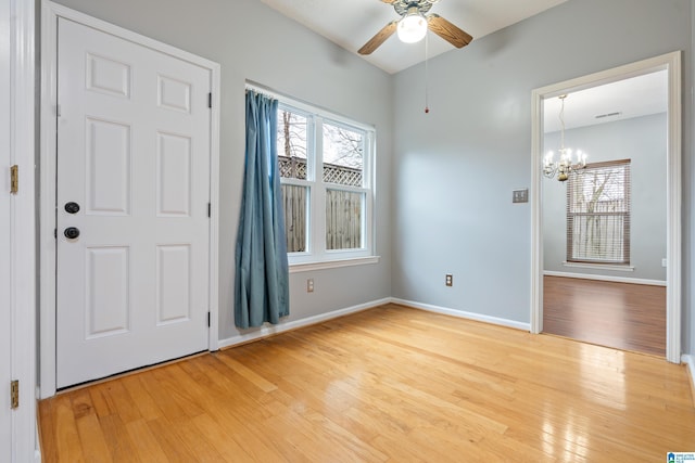 foyer entrance featuring visible vents, light wood-style flooring, ceiling fan with notable chandelier, and baseboards