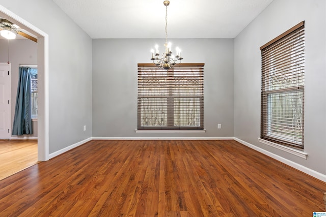 unfurnished room featuring a chandelier, plenty of natural light, and wood finished floors