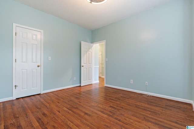 spare room with baseboards and wood finished floors