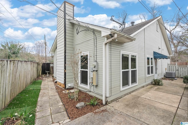 view of home's exterior featuring central AC, a fenced backyard, a chimney, and a patio area