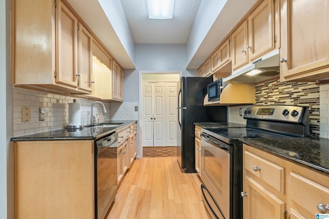 kitchen with under cabinet range hood, stainless steel electric range oven, dark stone counters, dishwashing machine, and light wood-style flooring