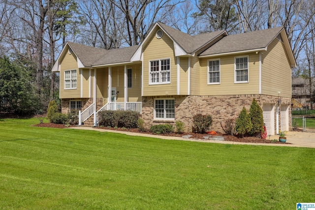 split foyer home with a front lawn, covered porch, concrete driveway, an attached garage, and brick siding