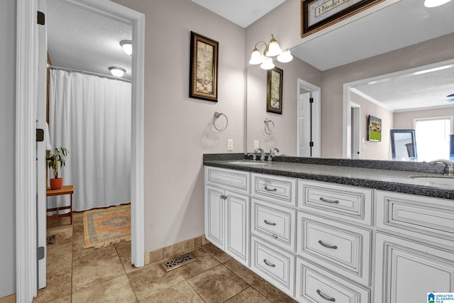 bathroom featuring a sink, baseboards, a textured ceiling, and double vanity