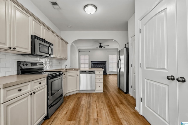 kitchen with visible vents, a peninsula, arched walkways, appliances with stainless steel finishes, and backsplash