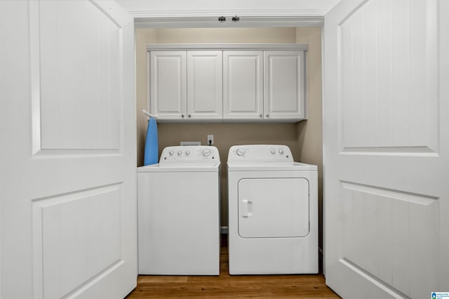 clothes washing area with wood finished floors, cabinet space, and washing machine and dryer