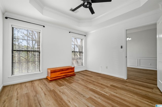 unfurnished room featuring a raised ceiling, crown molding, and a healthy amount of sunlight