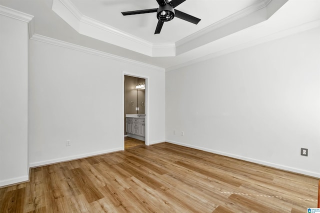 unfurnished room featuring baseboards, a tray ceiling, ornamental molding, light wood-style flooring, and a ceiling fan