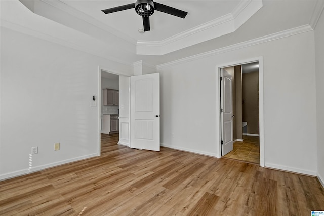 unfurnished bedroom featuring baseboards, light wood-style flooring, ceiling fan, ornamental molding, and a raised ceiling