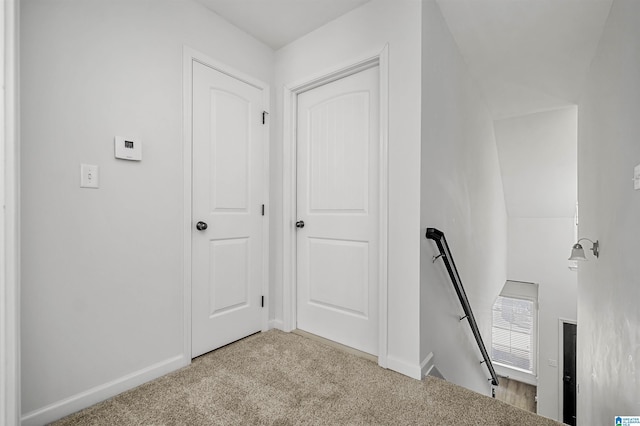 corridor featuring baseboards, an upstairs landing, and carpet