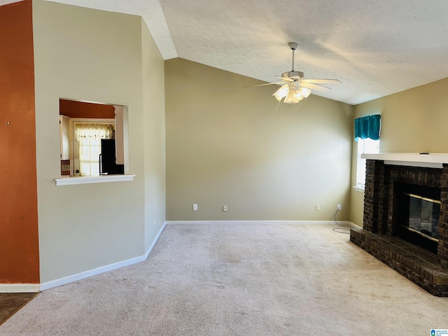 unfurnished living room featuring a ceiling fan, vaulted ceiling, a fireplace, and a healthy amount of sunlight