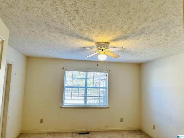 spare room with visible vents, light carpet, a textured ceiling, baseboards, and ceiling fan