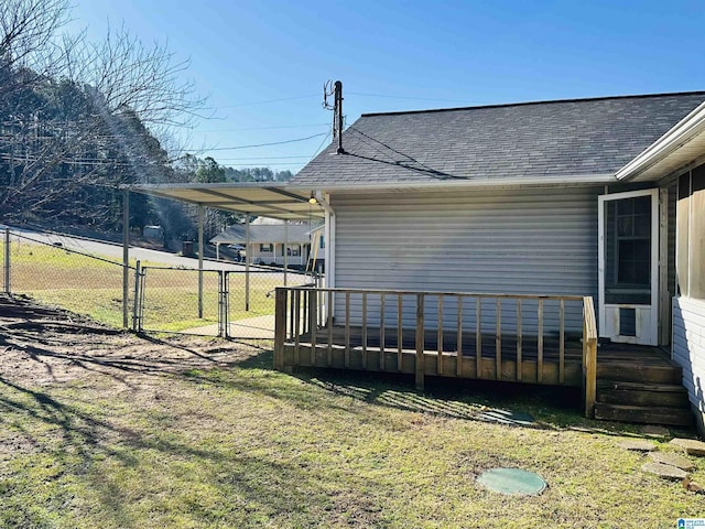 view of home's exterior featuring a lawn, a shingled roof, fence, and a gate